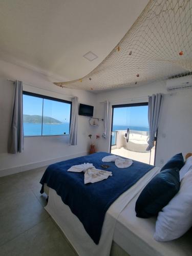 a bedroom with a bed with blue sheets and windows at Casa Corazul in Arraial do Cabo