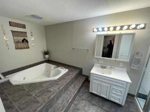 a bathroom with a bath tub and a sink at The Drover House by USAO in Chickasha, Fenced Yard, King Bed, Smart TV, High Speed WIFI & Covered Parking in Chickasha