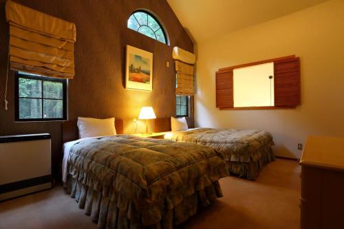 a hotel room with two beds and two windows at Hakuba Royal Suites in Hakuba