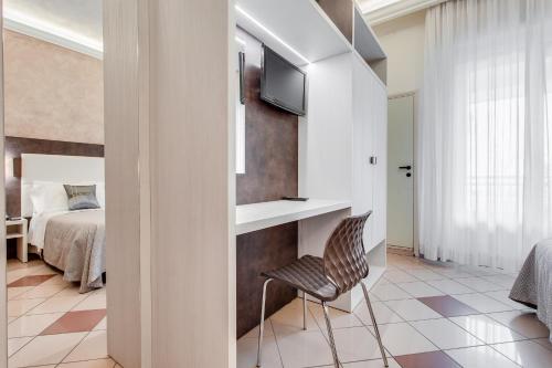 a room with a bed and a chair and a television at Hotel Dolcevita in Cesenatico