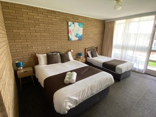 a hotel room with two beds and a brick wall at Warrina Motor Inn Wodonga CBD in Wodonga