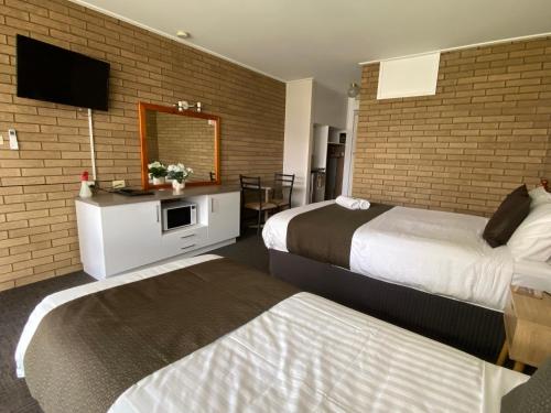 a hotel room with two beds and a tv at Warrina Motor Inn Wodonga CBD in Wodonga