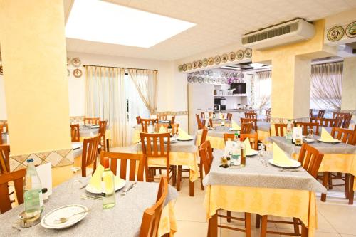a dining room with tables and chairs with yellow table cloth at Hotel Dolcevita in Cesenatico