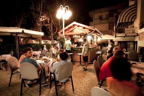a group of people sitting at a restaurant at night at Hotel Dolcevita in Cesenatico