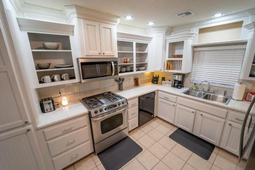 a kitchen with white cabinets and a stove top oven at The Drover House by USAO in Chickasha, Fenced Yard, King Bed, Smart TV, High Speed WIFI & Covered Parking in Chickasha