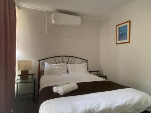a bedroom with a large bed with white sheets and pillows at Warrina Motor Inn Wodonga CBD in Wodonga