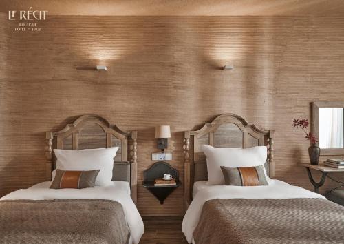 two beds in a hotel room with wooden walls at Le Récit Boutique Hôtel de Dalat in Da Lat