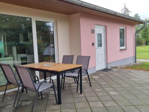 a table and chairs on a patio with a pink house at Reihenhaus am Groß Labenzer See, Klein Labenz in Klein Labenz