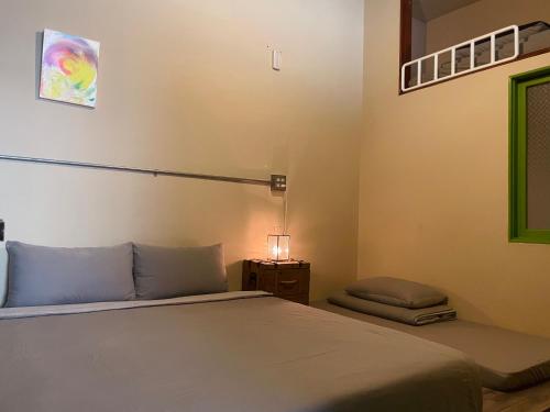 台南市にある米宿 Roomi House 台南老屋民宿のベッドとランプ付きのテーブルがある寝室