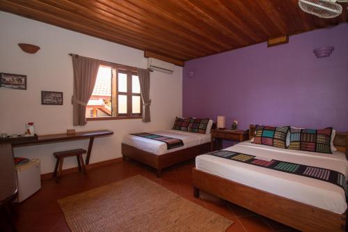 a bedroom with two beds and a desk and a window at TARA LODGE Haven of peace in Kep