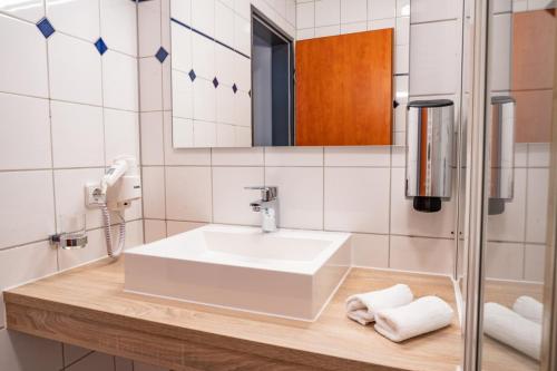 uma casa de banho com um lavatório branco e um espelho. em Hotel Müllers im Waldquartier em Bad Essen