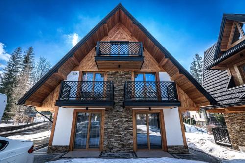 a house with a wooden roof and a balcony at Willa Trawers in Zakopane
