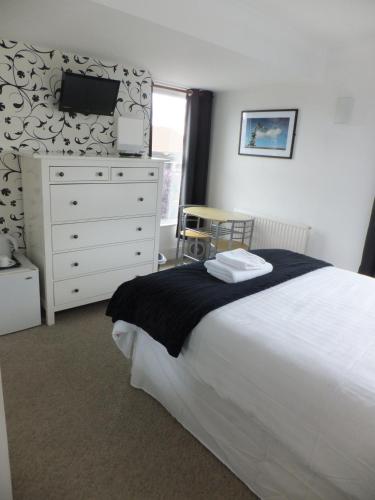 a bedroom with a bed and a dresser with a tv at Grove Guest House in Nottingham