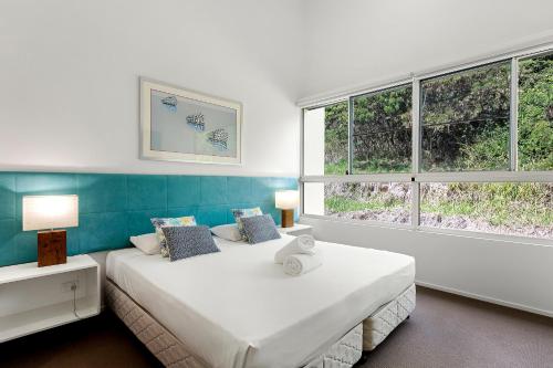 a bedroom with two beds and two windows at Azure Sea Whitsunday Resort in Airlie Beach