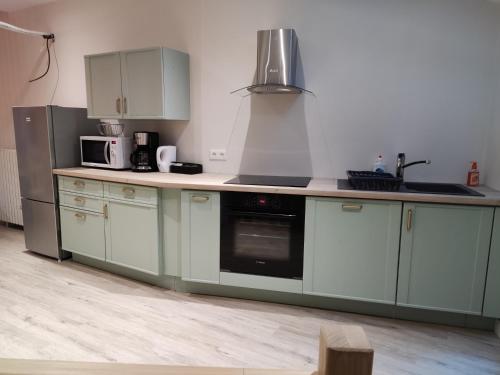 a kitchen with white cabinets and a stove top oven at Gîte L' Escale Ponote - Centre ville - Appart 90m2 in Le Puy en Velay