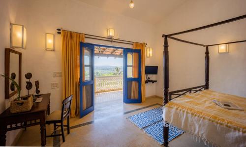 a bedroom with a bed and a desk and a door at Wildflower Villas - All Villa Hotel, Family Run in Candolim