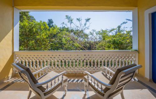 two chairs on a balcony with a large window at Wildflower Villas - All Villa Hotel, Family Run in Candolim