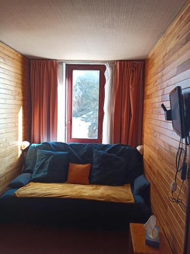 a living room with a blue couch in front of a window at Studio transformé en 2 pièces avec cloison amovible sur La Plagne Bellecôte in Sangot