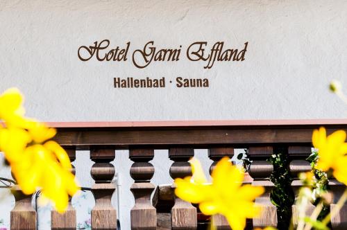 a sign on a wall with yellow flowers at Hotel Effland -Sauna -Pool in Bayrischzell