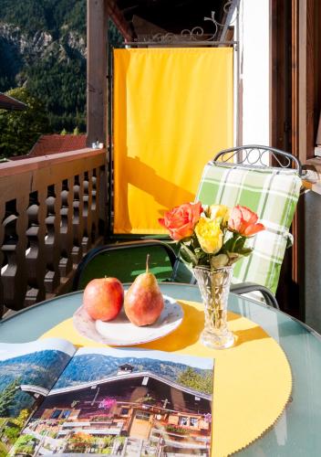 a table with a vase of apples and flowers on it at Hotel Effland -Sauna -Pool in Bayrischzell