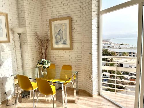 une salle à manger avec une table en verre et des chaises jaunes dans l'établissement Apartamento Torre de la Roca Torremolinos, à Torremolinos