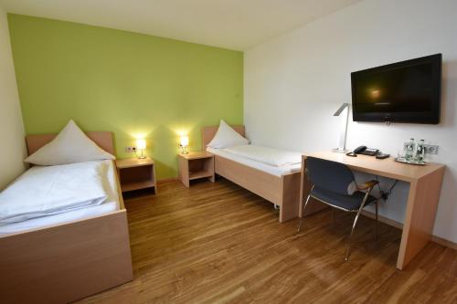 a room with two beds and a desk with a computer at Hotel Kranz in Gottmadingen