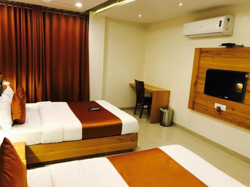 a hotel room with a bed and a television at Hotel Grandeur-Near Mumbai International Airport in Mumbai