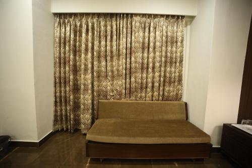 a couch in front of a window with a curtain at The Byke Heritage Resort - Matheran in Matheran