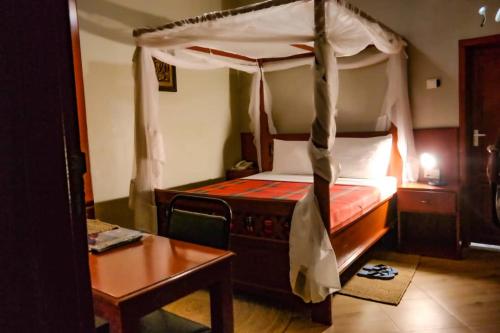 a bedroom with a canopy bed and a table at Parachichi House BNB in Arusha