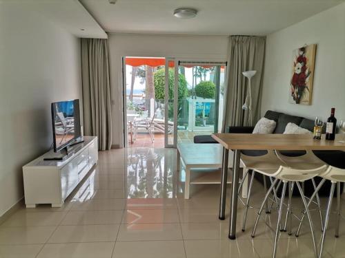 een woonkamer met een televisie en een tafel en stoelen bij SEA VIEW APARTMENTS in Costa Calma