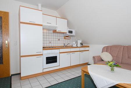 a kitchen with a couch and a table in a room at Ferienwohnungen im Huus Janssand in Bensersiel