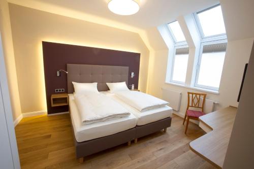a bedroom with a large bed in a room with windows at Genießerhotel Limbacher in Herrieden