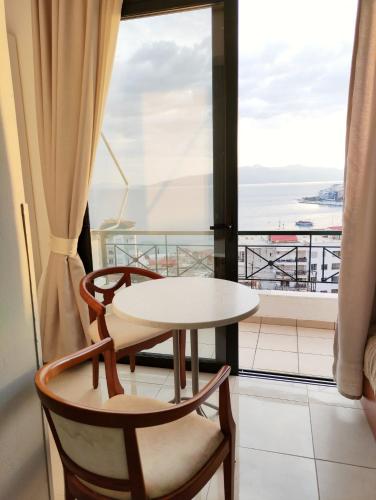 a table and chairs in a room with a window at Olympia Hotel in Sarandë