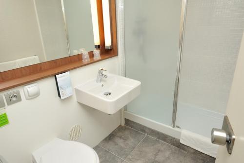 a bathroom with a sink and a toilet and a mirror at Campanile Annecy - Cran Gevrier in Annecy