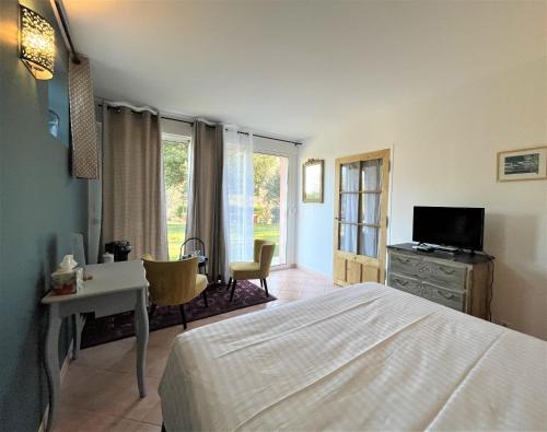 a bedroom with a bed and a desk and a television at Le Mas Carré Séguret in Séguret