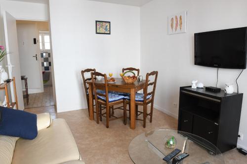 ein Wohnzimmer mit einem Tisch und Stühlen sowie einem TV in der Unterkunft La Belle Onde in Dieppe