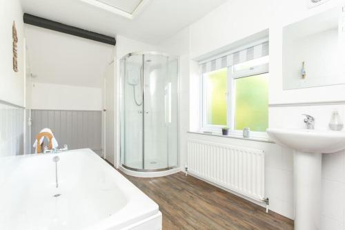 a white bathroom with a shower and a sink at Drovers Cottage in Tavistock