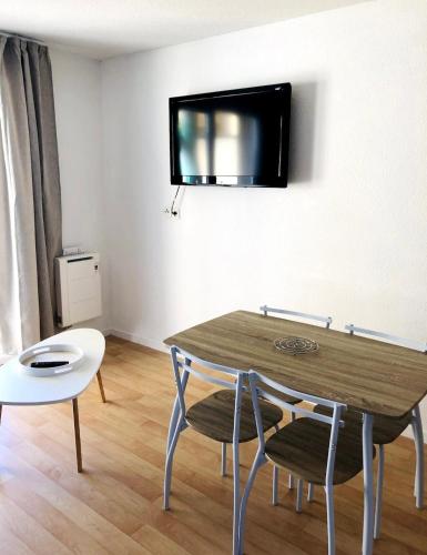 un salon avec une table et une télévision au mur dans l'établissement Les Terrasses, à Cayeux-sur-Mer