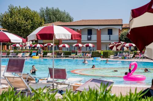 a pool at a hotel with people swimming in it at Pini Village Lido Altanea in Caorle