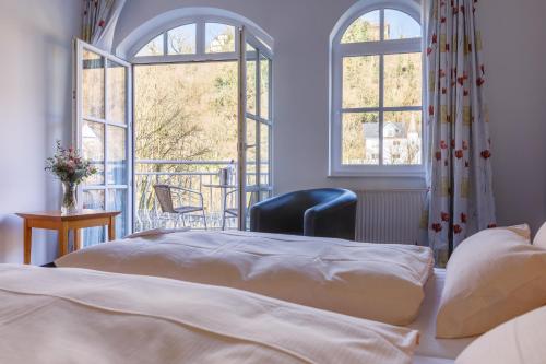 a bedroom with a bed and a balcony with windows at Hotel Lahnschleife in Weilburg