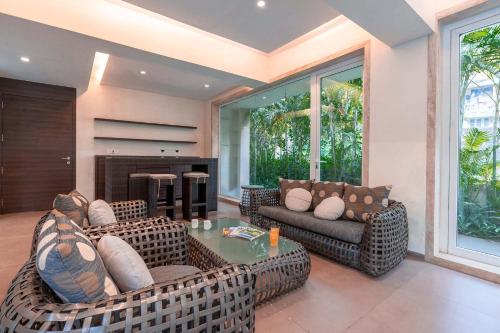 a living room with wicker furniture and a fireplace at StayVista's Bianco Villa - Hill-View Villa with Private Pool, Jacuzzi, Gym & Games Room in Lonavala