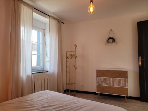 a bedroom with a bed and a window and a dresser at Maison rénovée au calme in Dannevoux