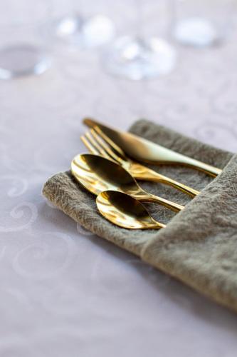 a group of gold forks and spoons on a napkin at Hotel Victoria in Skellefteå