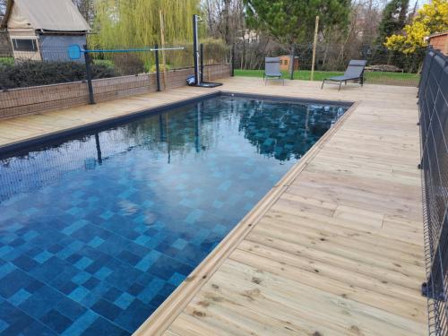 - une piscine avec du carrelage bleu sur une terrasse en bois dans l'établissement Au Petit Pédegouaty, à Heugas