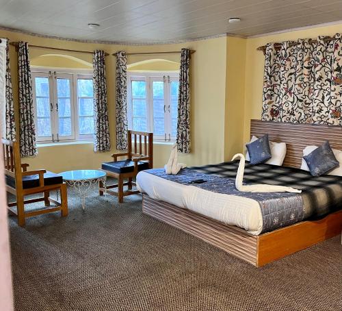 Un dormitorio con una cama y una silla y ventanas. en Hotel Ashai, en Srinagar