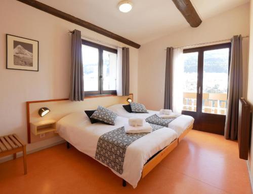 2 camas en una habitación con 2 ventanas en ULVF Les Essertets, en Praz-sur-Arly