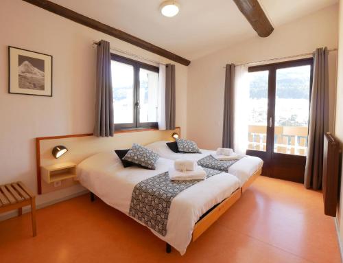 two beds in a room with two windows at ULVF Les Essertets in Praz-sur-Arly