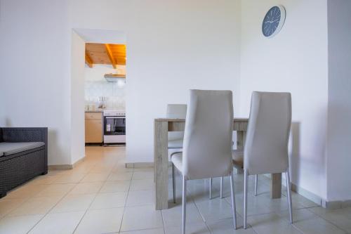 a dining room with a table and four white chairs at At The Messinian's Bay in Velíka