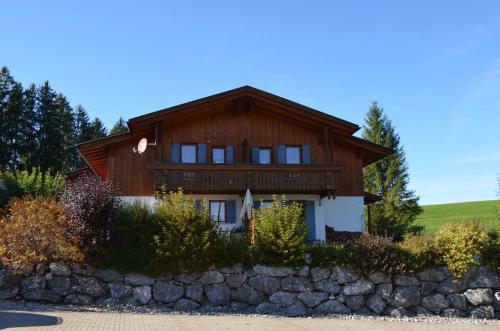 a large wooden house with a stone wall at Feriendorf Via Claudia Haus 100 Dominique in Lechbruck