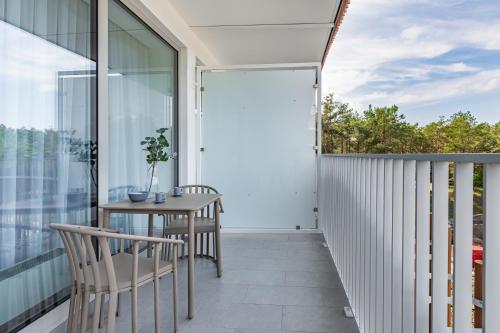 balkon z drewnianym stołem i krzesłami w obiekcie Apart Park - Stylowe Studio 3 min od PLAŻY by Noclegi Renters w Świnoujściu